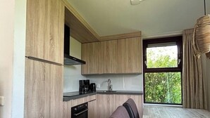 Una cocina moderna con armarios de madera, horno empotrado y zona de comedor con banco.