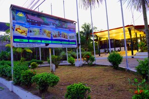 Un hotel con un gran cartel que anuncia servicios como piscina, restaurante y salones para conferencias.