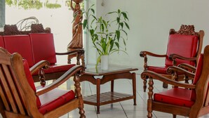 Une pièce avec des chaises en bois et une table, une plante en pot et une statue.