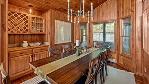 Un interior de madera con una mesa de comedor, sillas y una araña.
