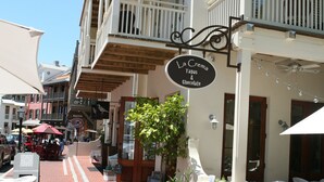 Una calle con mesas al aire libre, un letrero que anuncia La Crema: tapas y chocolate, y un menú en una pizarra.