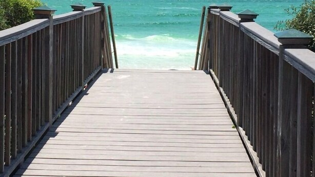 Una pasarela de madera que conduce al océano, con una vista despejada del mar.