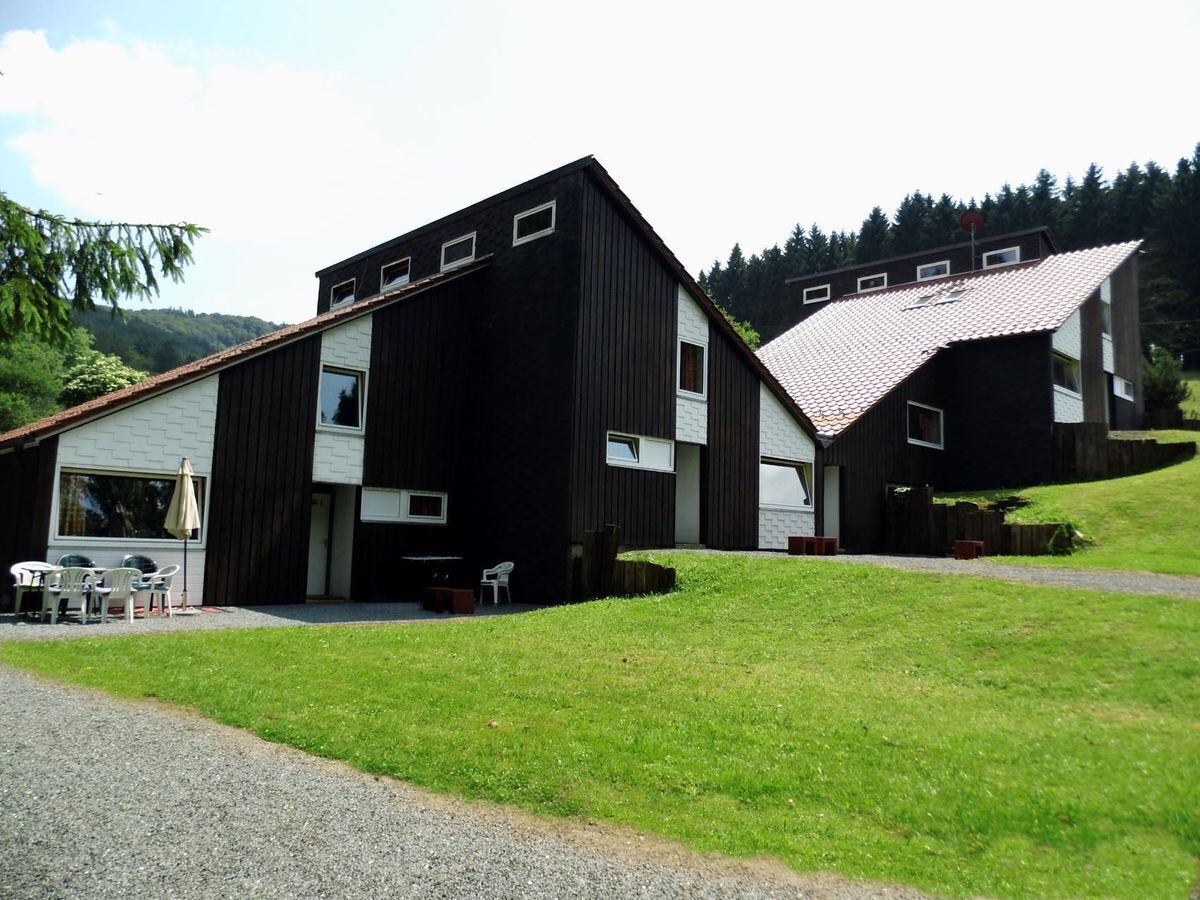 A two-story building with a gravel driveway and a grassy area in front.