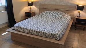 A modern bedroom with a wooden bed, patterned bedding, two bedside lamps, a round mirror, and a textured wall. - House with private pool, not shared between Vaison la Romaine and Nyons (Saint-Maurice-sur-Eygues.)