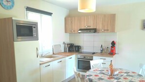 A compact kitchen with a microwave, oven, sink, and a dining table with chairs. - House with private pool, not shared between Vaison la Romaine and Nyons (Saint-Maurice-sur-Eygues.)