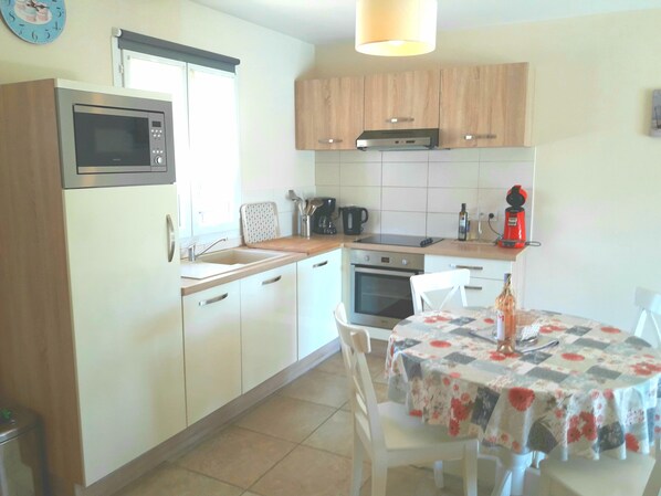 Una cocina compacta equipada con microondas, horno, pileta y una mesa de comedor con sillas.