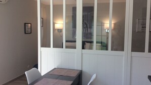 A dining area with a table and chairs, a wall-mounted air conditioner, and framed artwork. - Air-conditioned studio with charming little garden in Villeneuve les Avignon (Villeneuve-Lès-Avignon)