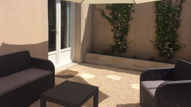 An outdoor seating area with a white umbrella, wicker furniture, and a gravel floor. - Air-conditioned studio with charming little garden in Villeneuve les Avignon (Villeneuve-Lès-Avignon)