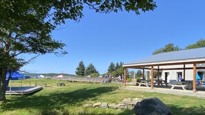 An outdoor area with picnic tables, a covered pavilion, and a stage. - A Historic Storybook Maine Cottage (New Harbor)