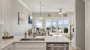 Una cocina moderna con una isla central, electrodomésticos de acero inoxidable y vistas al exterior.
