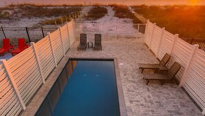 Un área de piscina con vista a la playa al atardecer.