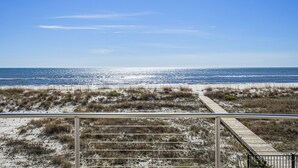 Vista a la playa con un paseo marítimo de madera que llega a la orilla.