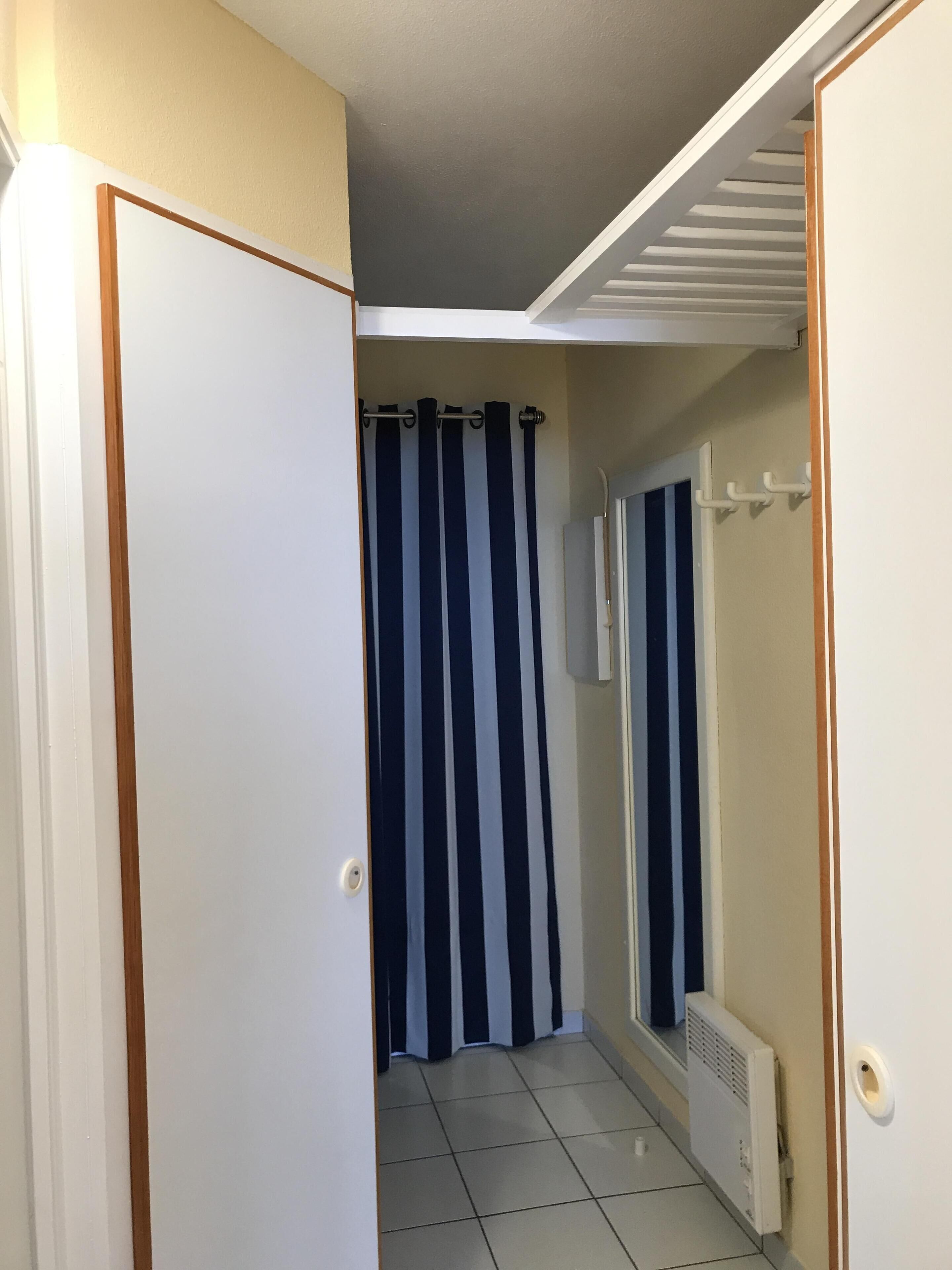 A narrow hallway with a tiled floor, a white door on the left, and a white radiator on the right.
