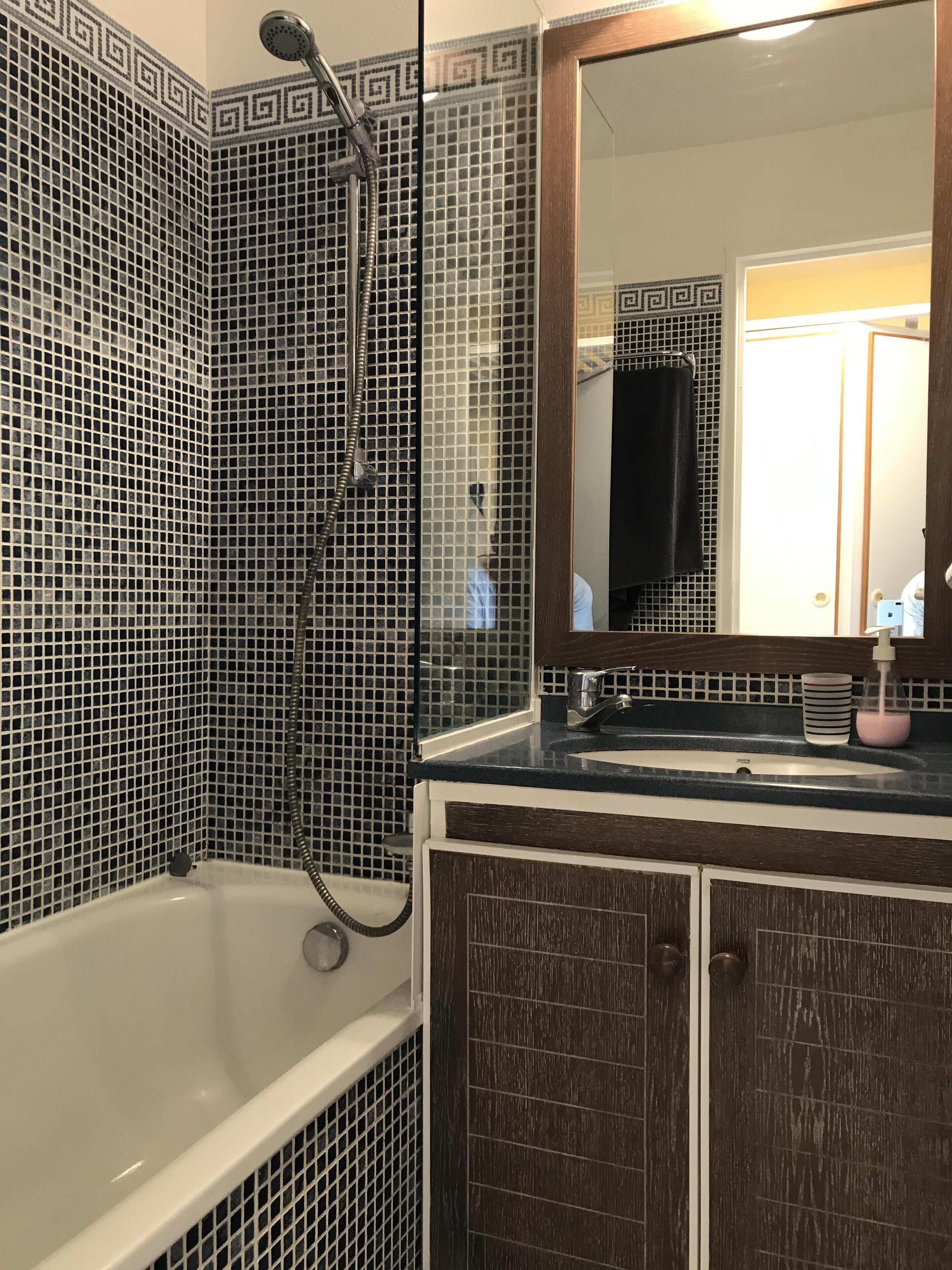 Une salle de bain équipée d’une baignoire, d’une douche et d’un lavabo avec un miroir au-dessus.
