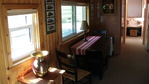 A wooden interior with a dining table, chairs, a lamp, and a window. - Cozy, Quiet, Getaway for Single or Couple (Big Bay)