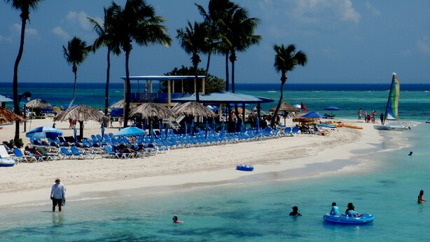 A beach with clear turquoise water, palm trees, and a beach umbrella area with lounge chairs. - BEACHFRONT > 5 STAR > 2 LEVEL PENTHOUSE VILLA > MAGNIFICENT PANORAMIC VIEWS  (Barrio Las Cabezas, Fajardo)