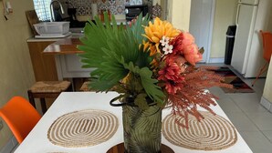A dining table with a white tablecloth, a vase with flowers, and woven placemats.