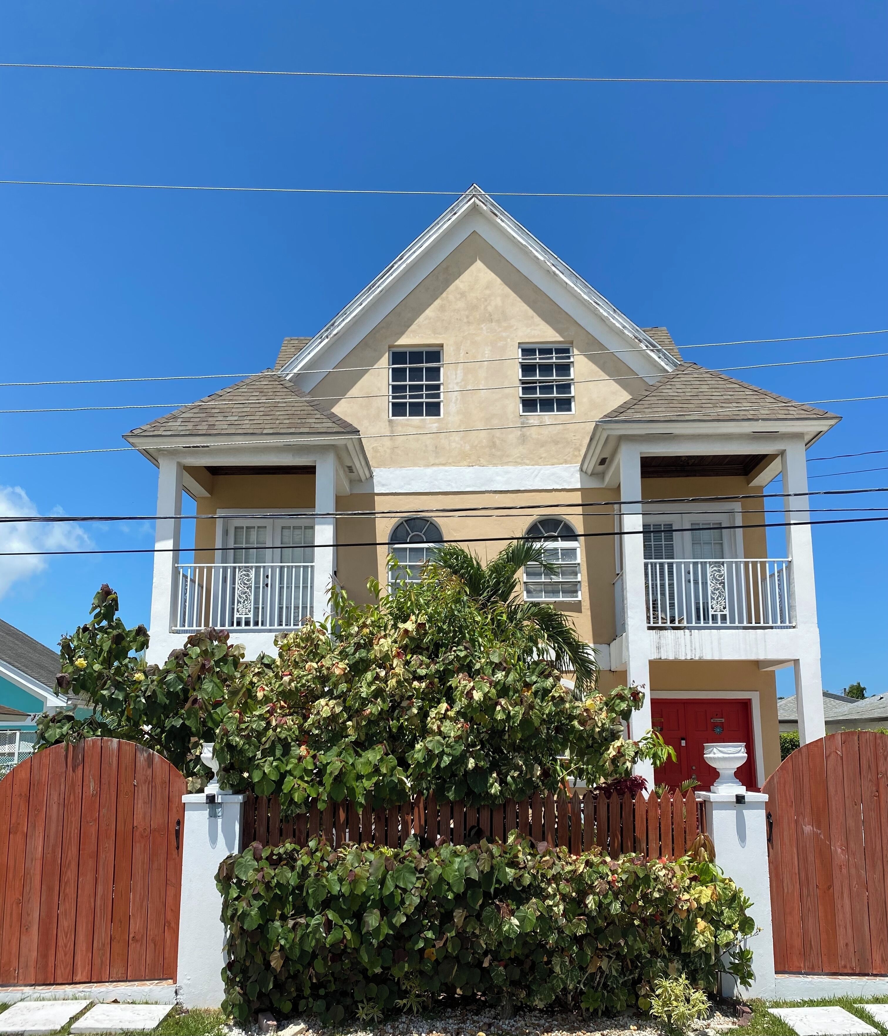 A two-story house with a beige facade, white trim, and a red door.