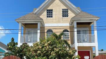 A two-story house with a beige facade, white trim, and a red door.