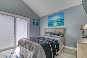 Une chambre à coucher avec un lit, un tableau, une lampe et une fenêtre avec des stores.