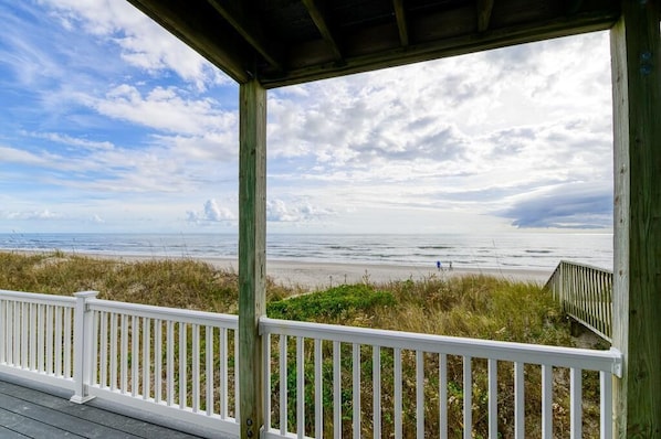 Une terrasse en bois avec une balustrade blanche donnant sur une plage.