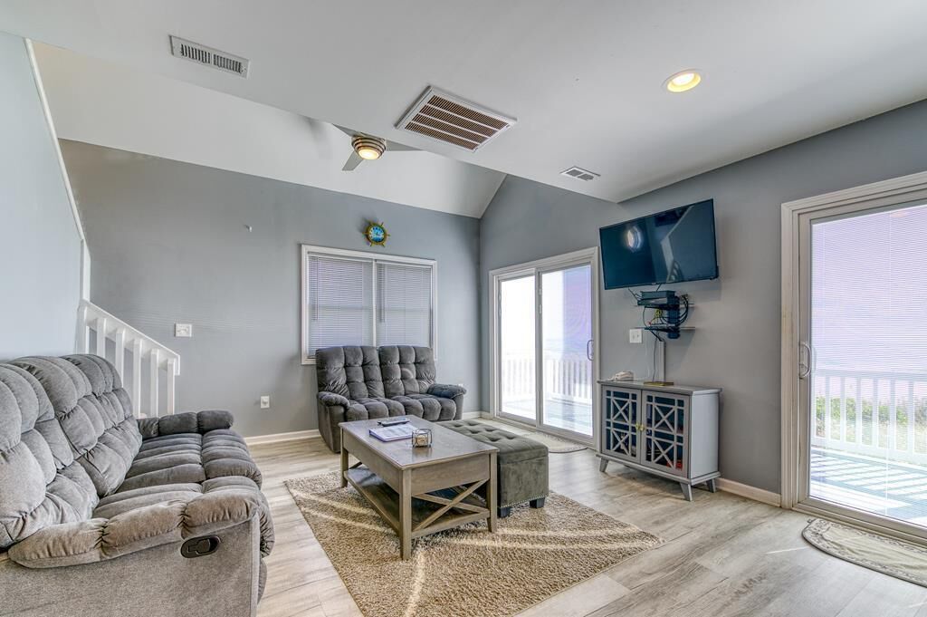 A living room with a gray sofa, a gray armchair, a wooden coffee table, and a TV on the wall.