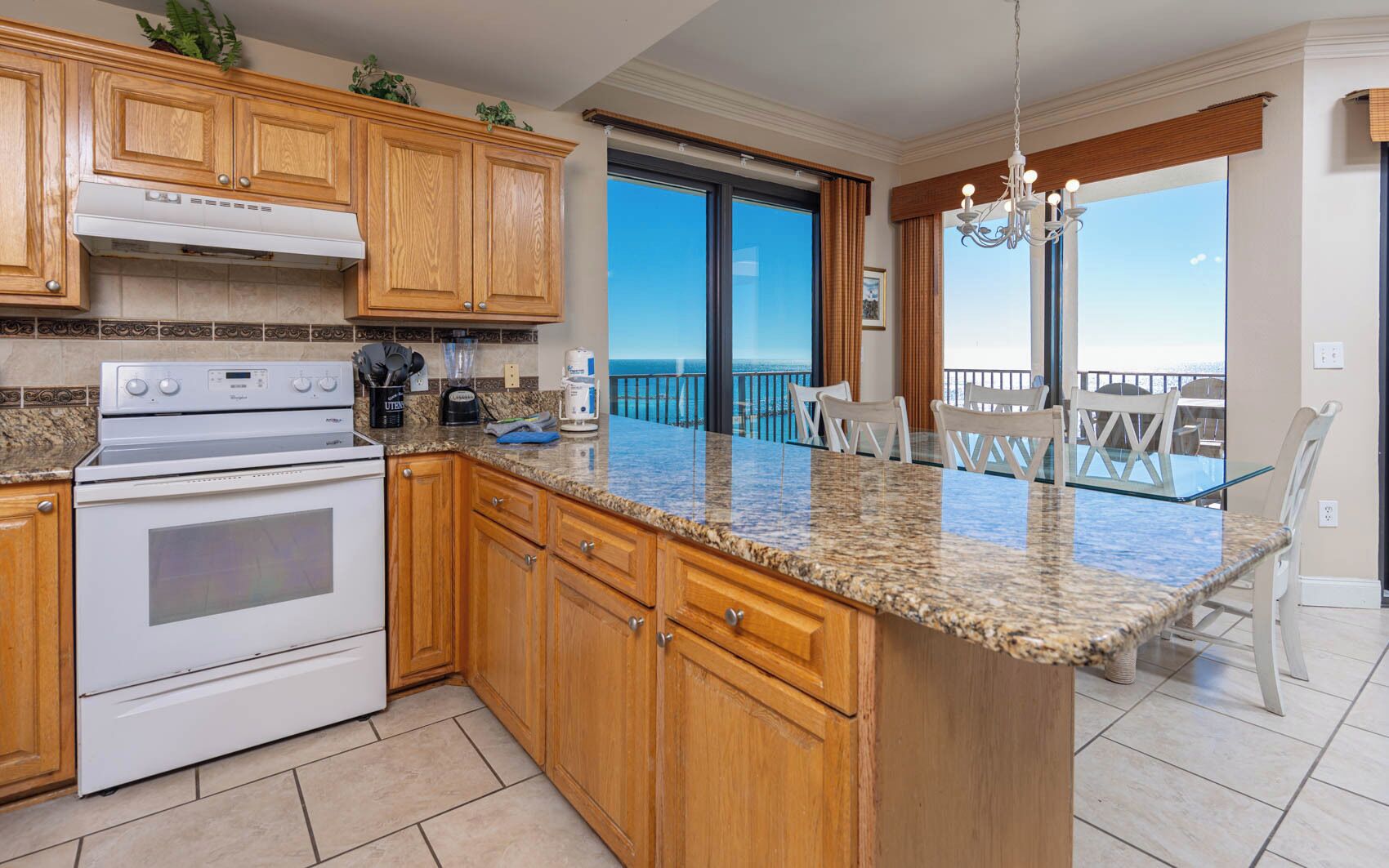 A kitchen with wooden cabinets, a granite countertop, and a view to the outside.