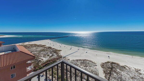 A beach view from a balcony with a clear sky, sandy beach, and a pier extending into the sea. - Three Bedroom at Phoenix East II - Condo #2155 (Orange Beach)