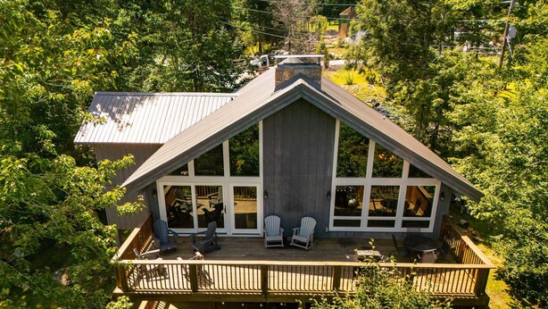 A house with a large deck, multiple windows, and a chimney. - Historic Beech Mountain Lodge | Hot Tub | Game Room | Sleeps 19 (Beech Mountain)