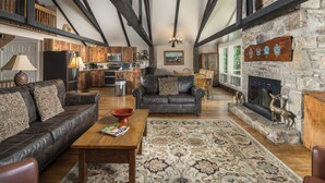 A spacious living area with a fireplace, a stone wall with heraldic shields, and a cozy seating arrangement. - Historic Beech Mountain Lodge | Hot Tub | Game Room | Sleeps 19 (Beech Mountain)
