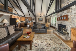 A spacious living area with a fireplace, a stone wall with heraldic shields, and a cozy seating arrangement. - Historic Beech Mountain Lodge | Hot Tub | Game Room | Sleeps 19 (Beech Mountain)