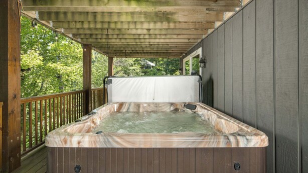 A hot tub under a wooden pergola with a view of trees. - Historic Beech Mountain Lodge | Hot Tub | Game Room | Sleeps 19 (Beech Mountain)