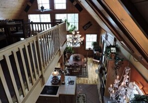 Ein großzügiger Loft-Raum mit hohen Decken, Holzbalken, einem Essbereich, einer Küche mit Spüle und einer Kristallleuchtre.