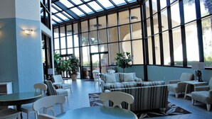 A spacious indoor area with a high ceiling, large windows, and a variety of seating arrangements including sofas and chairs. - Fun in the Sun! 3 bdrm/2 Bath Ocean Front Condo with gorgeous views of the Gulf! (Orange Beach)