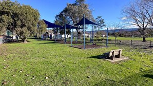 A park with a playground, a bench, and trees. - Snowy Mtn Lake Cottage | Pets & Groups | Sleeps 8 (Talbingo)