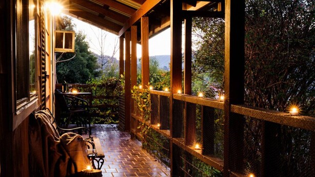 A covered outdoor seating area with a wooden bench, a table, and string lights. - Snowy Mtn Lake Cottage | Pets & Groups | Sleeps 8 (Talbingo)