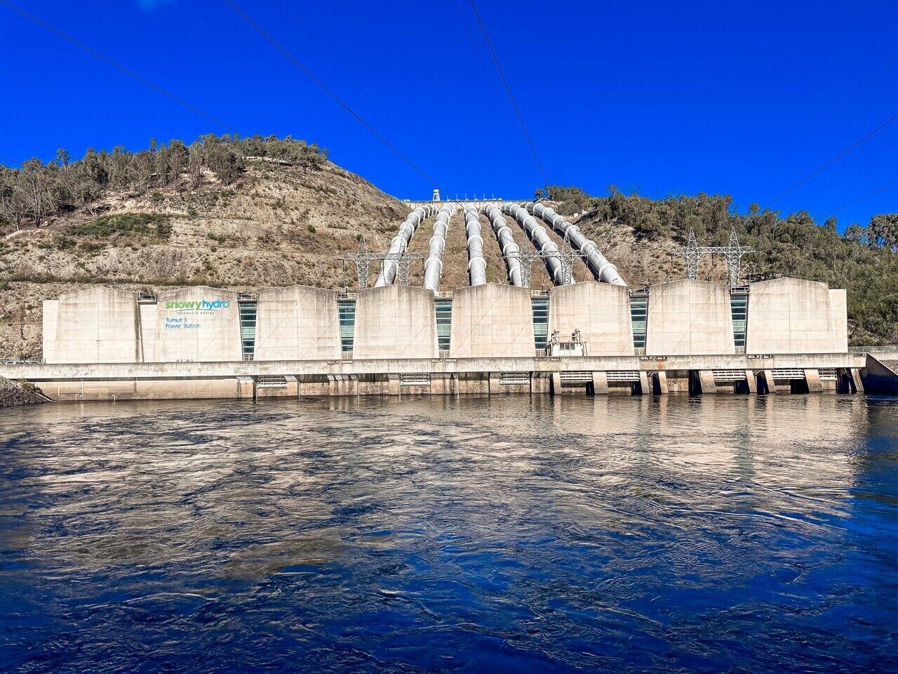 Una estructura de concreto con varios tubos y un cuerpo de agua al frente.