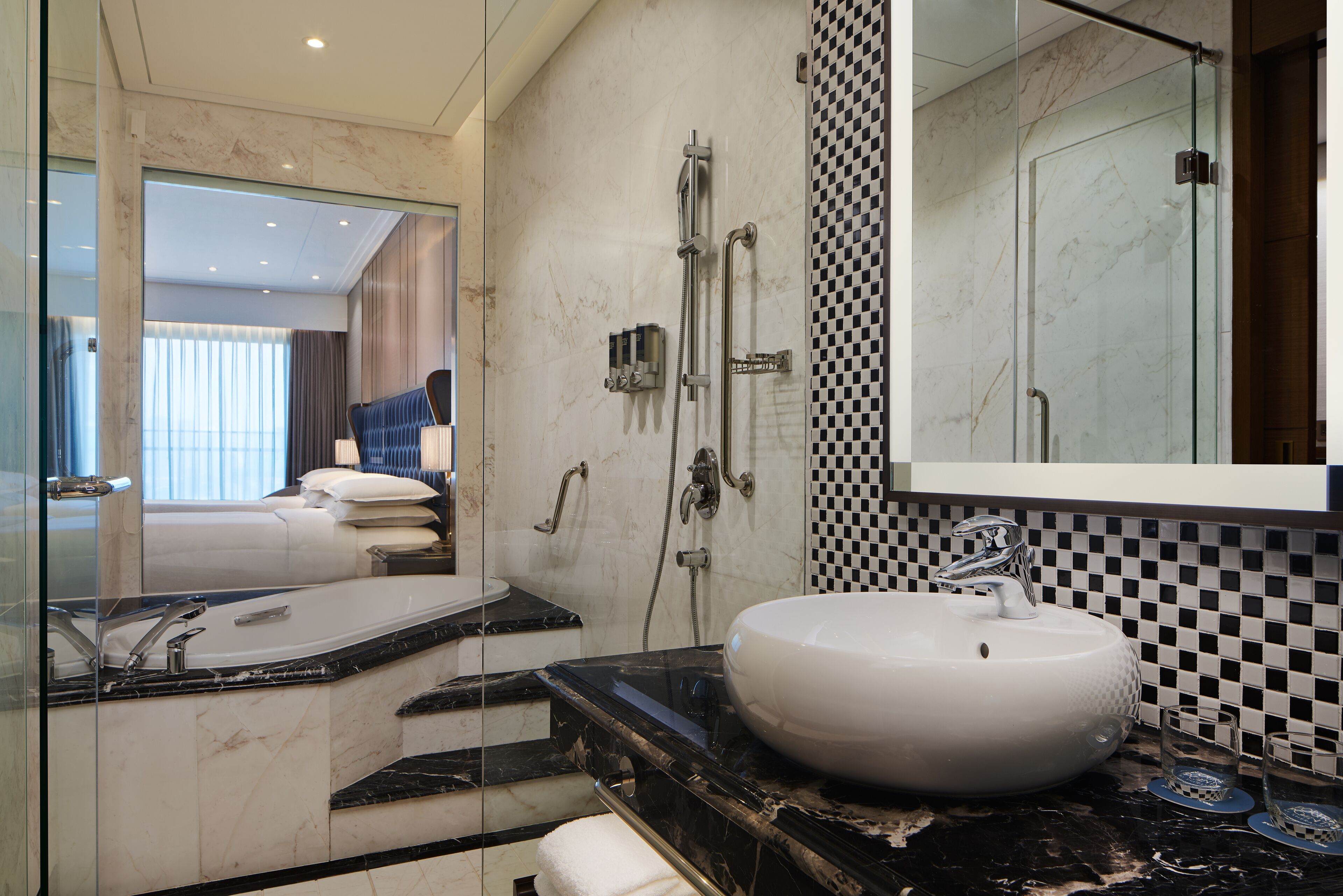 A modern bathroom with a large mirror, a white sink, and a shower area.