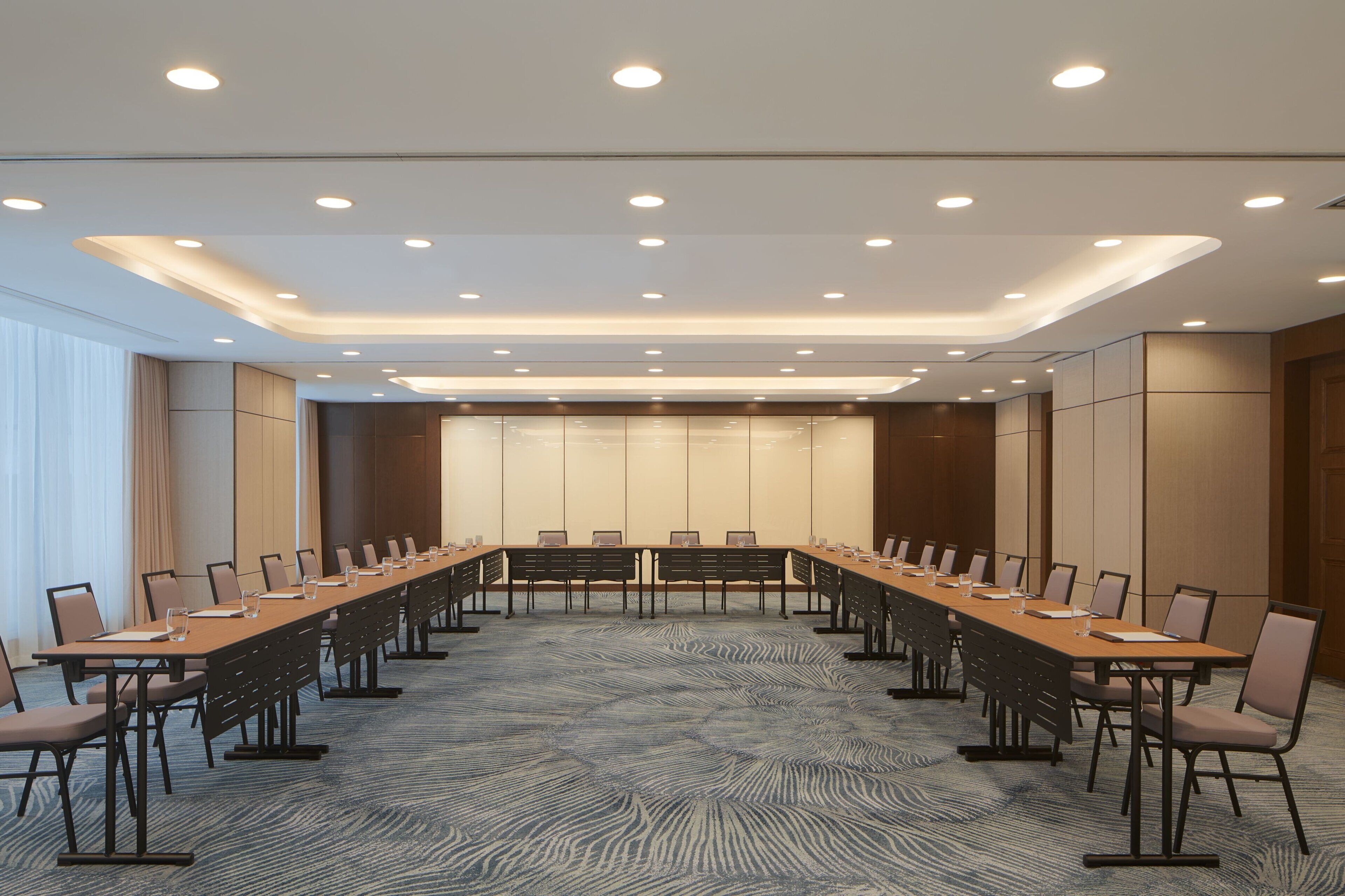 A conference room with a long table, chairs, and a carpeted floor.