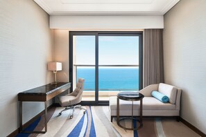 A hotel room with a desk, chair, sofa, and a view of the ocean. - Four Points by Sheraton Danang (Da Nang)