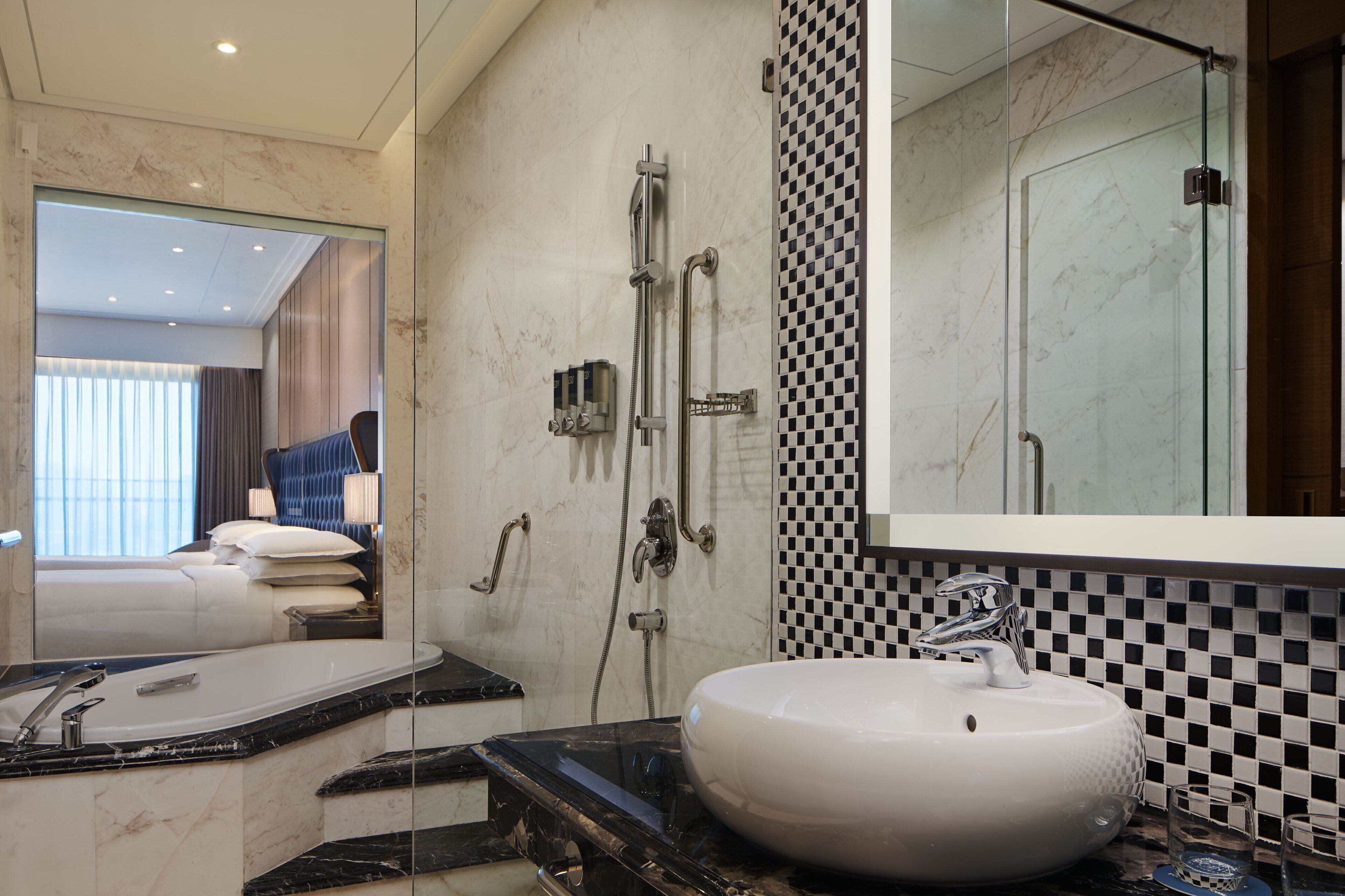 A modern bathroom with a large mirror, a white sink, and a shower area.