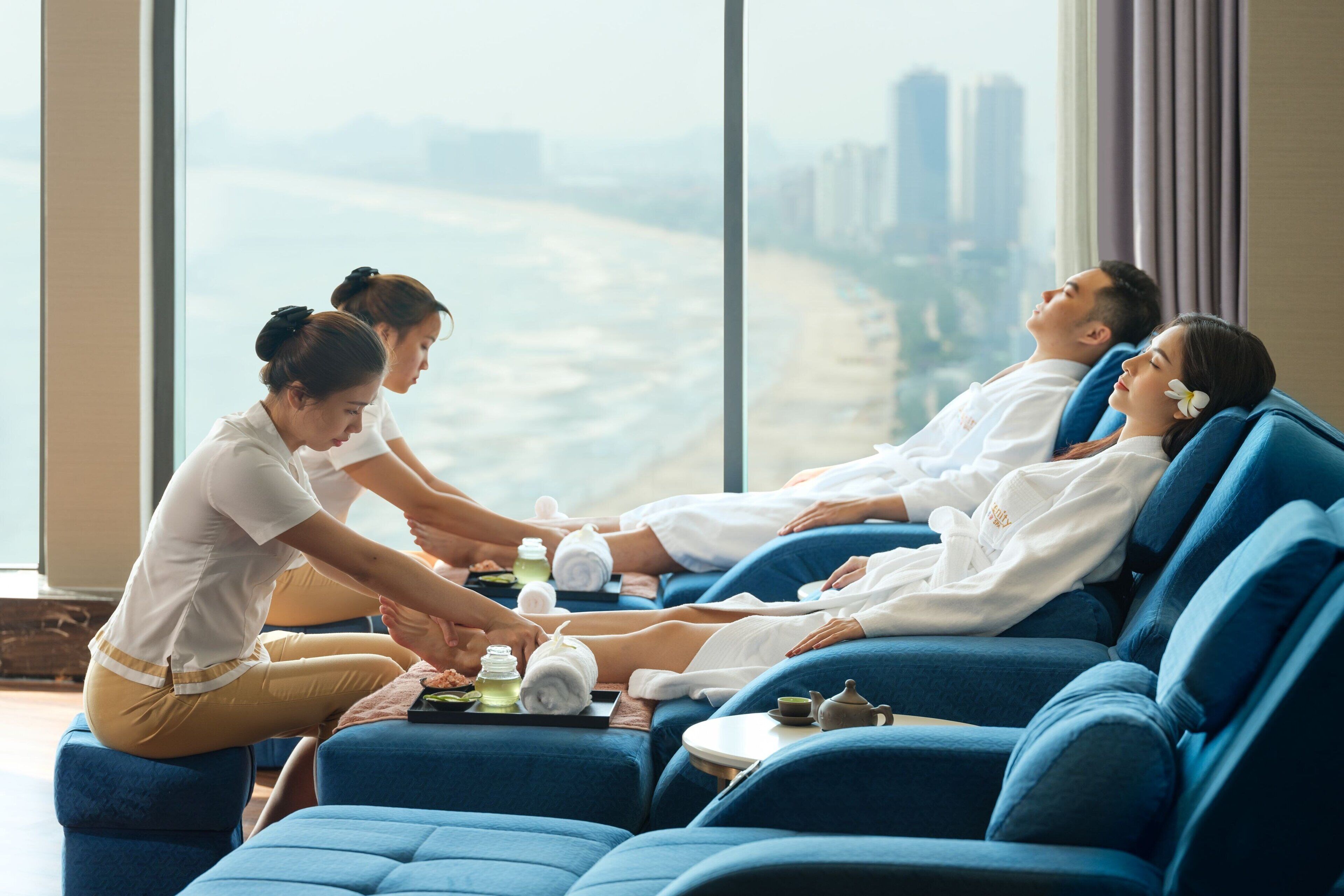 A massage parlor with blue massage chairs and a view of a beach and buildings.