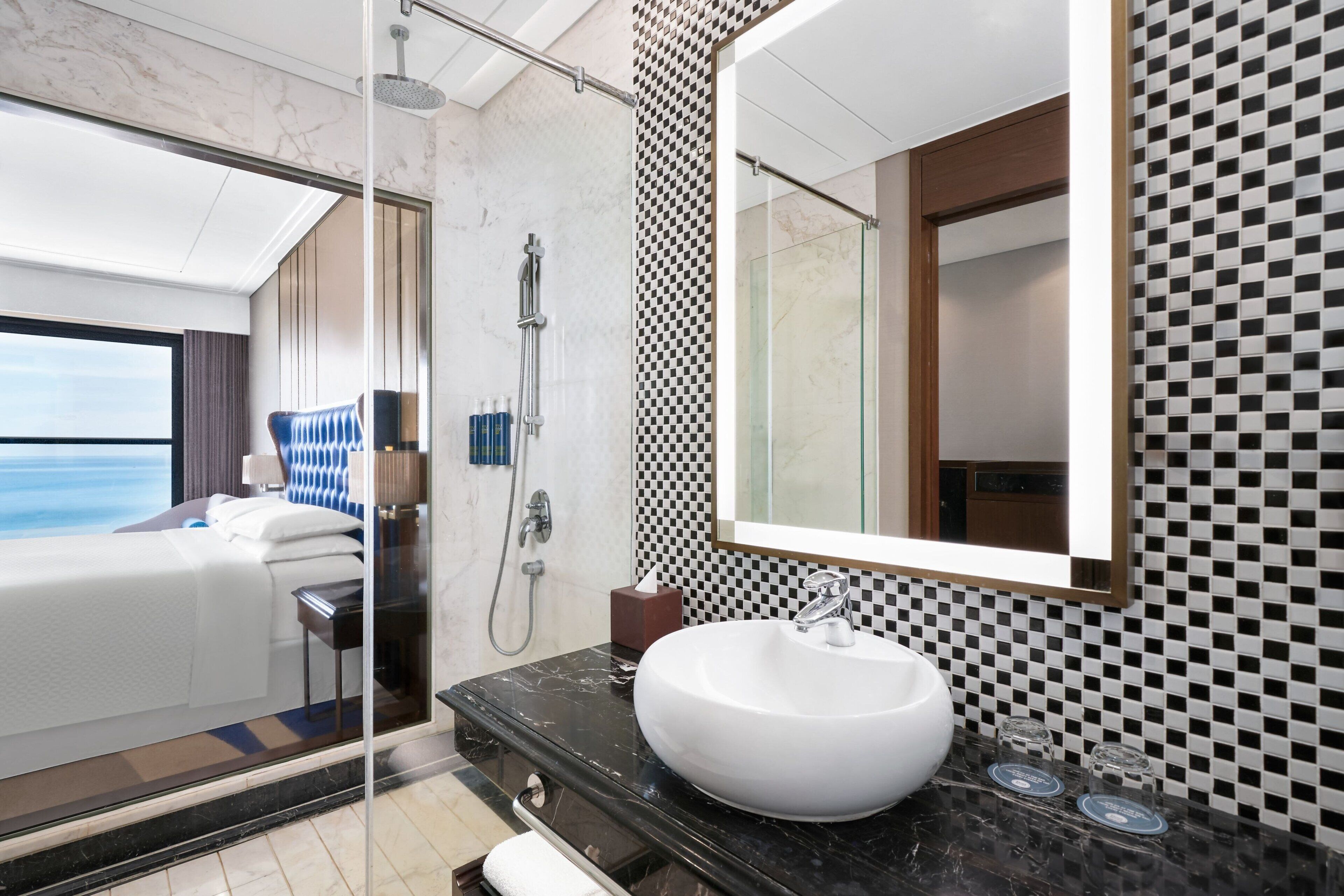 A modern bathroom with a large mirror, a white sink, and a shower area.