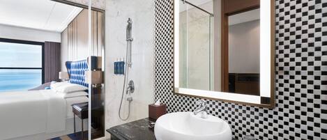 A modern bathroom with a large mirror, a white sink, and a shower area.