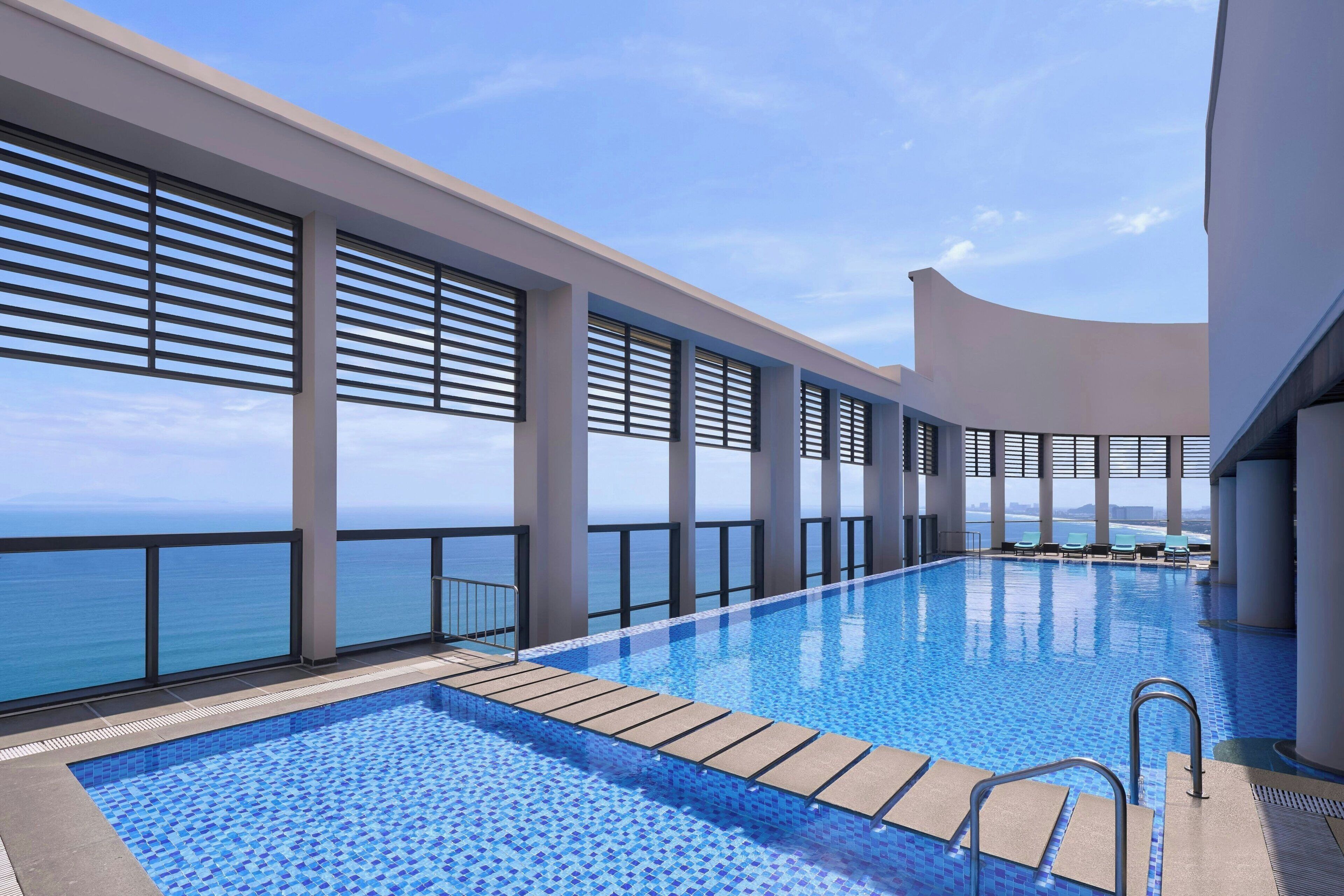 A modern infinity pool with a clear view of the ocean, large windows, and a minimalist design.