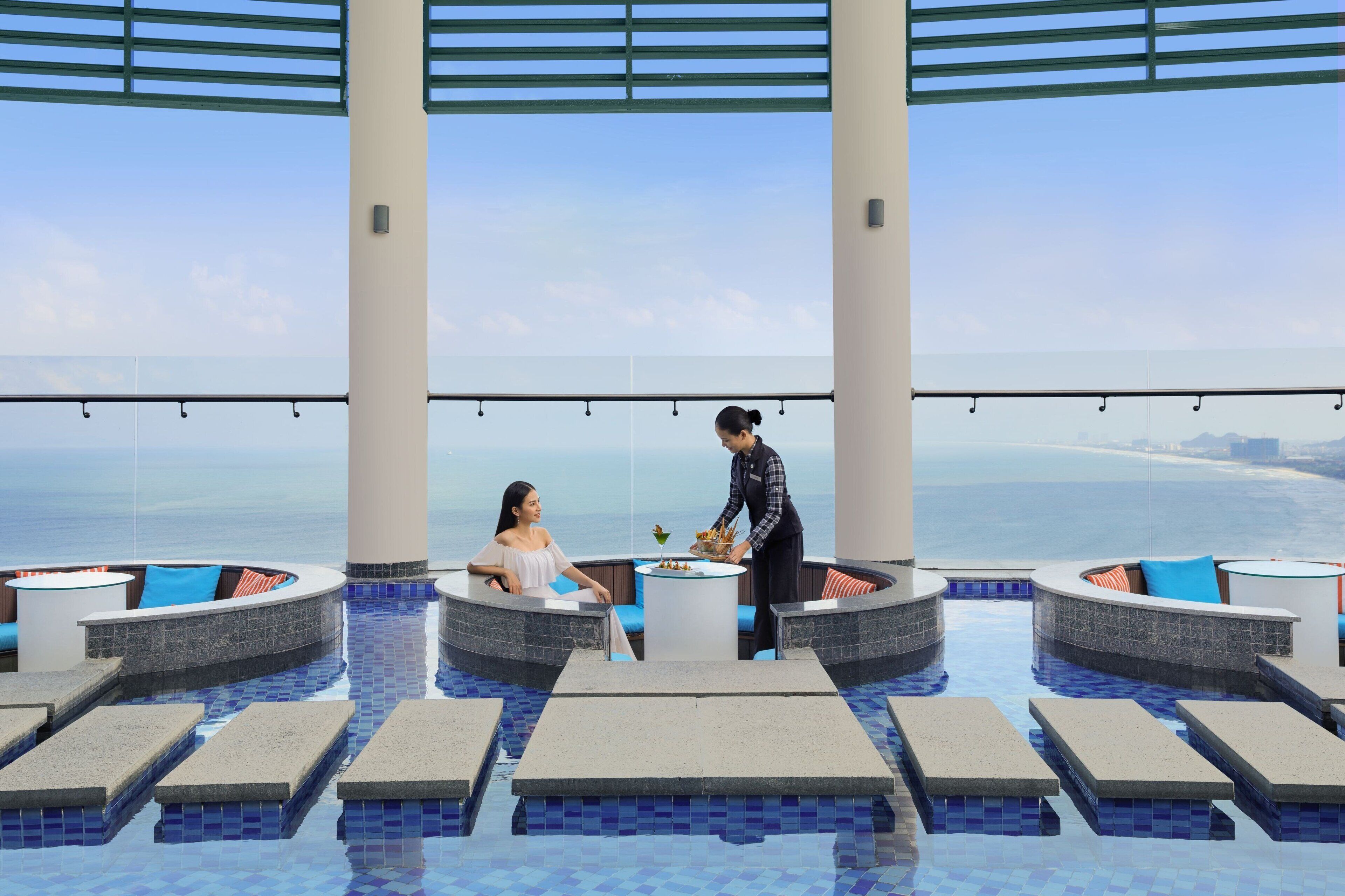 A poolside area with seating and a waiter serving a guest.