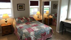 A bedroom with a large bed, two bedside tables with lamps, a desk, and a mirror. - Oysterbay Cottage - Fun, Beach and Food!!! License number 2100974 (Darnley)