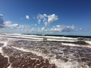 A beach with waves and a clear sky.