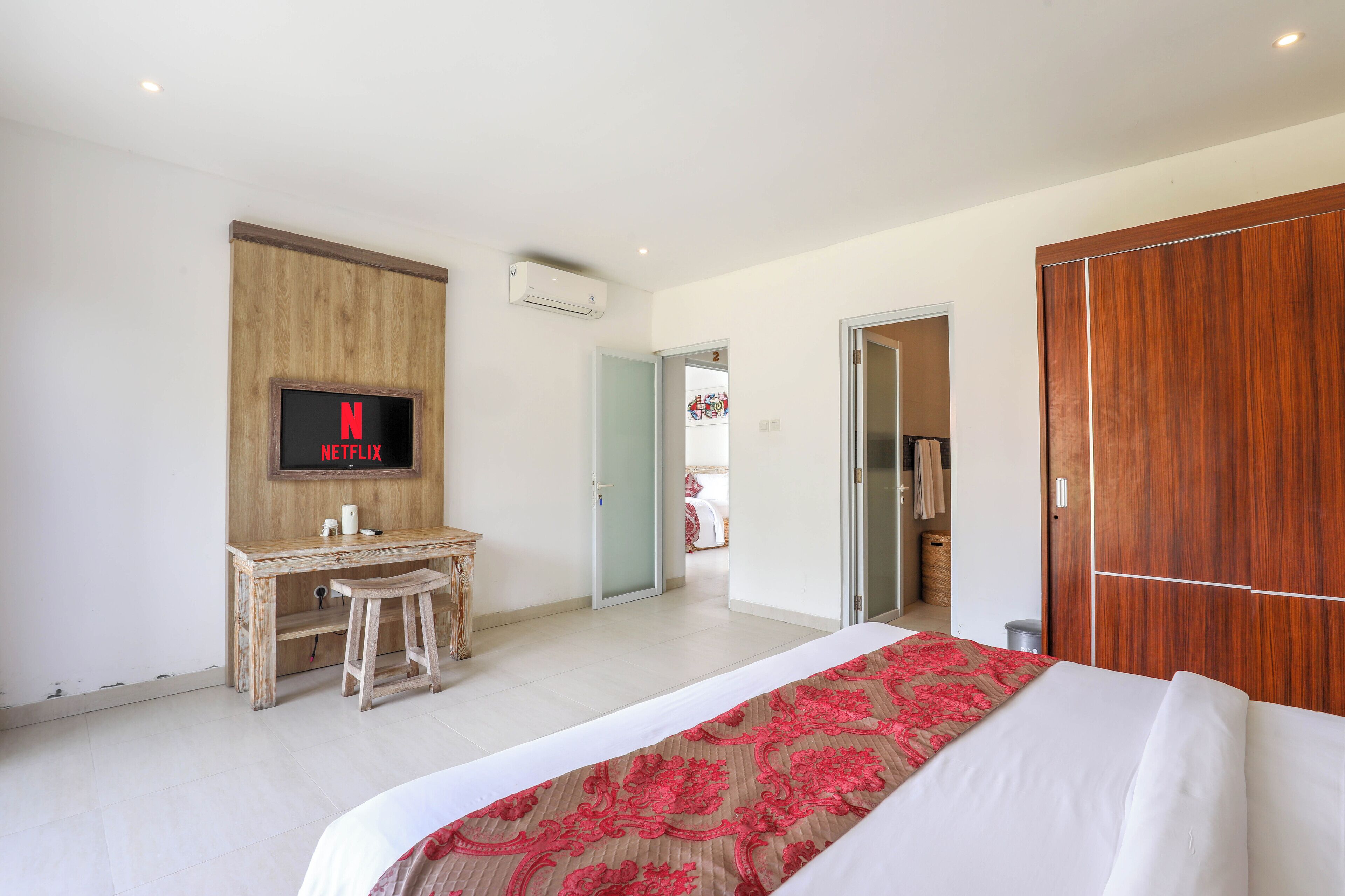 Ein Hotelzimmer mit einem Bett, einem Schreibtisch mit Stuhl, einem an der Wand befestigten Fernseher und einem Kleiderschrank.