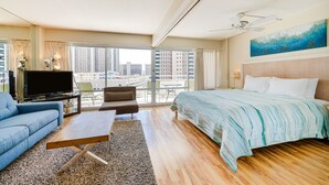 Et moderne hotelværelse med en stor seng, en sofa, et fjernsyn og en balkon med udsigt over byen.